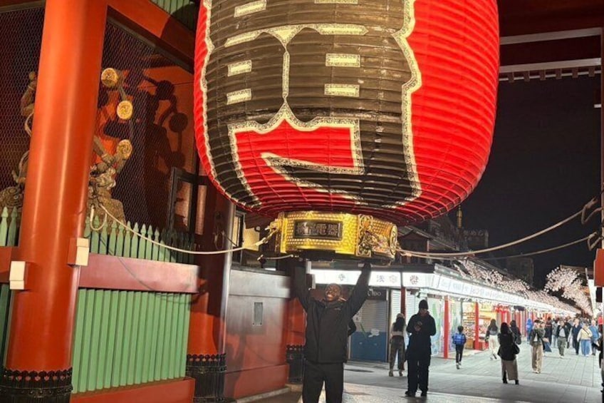 A traditional lantern being carried by a person, with a crowd in the background. 5