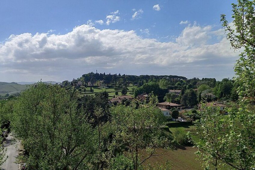 A rural landscape with rolling hills, scattered houses, and a prominent hilltop structure. 4