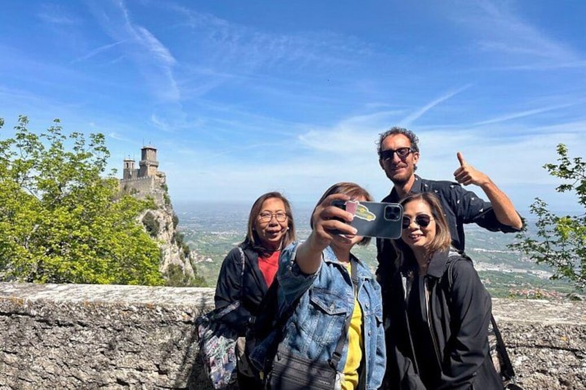 A group of people taking a selfie with a historic castle in the background. 1