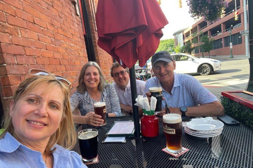 A group of people sitting at an outdoor table with drinks and a menu. 1