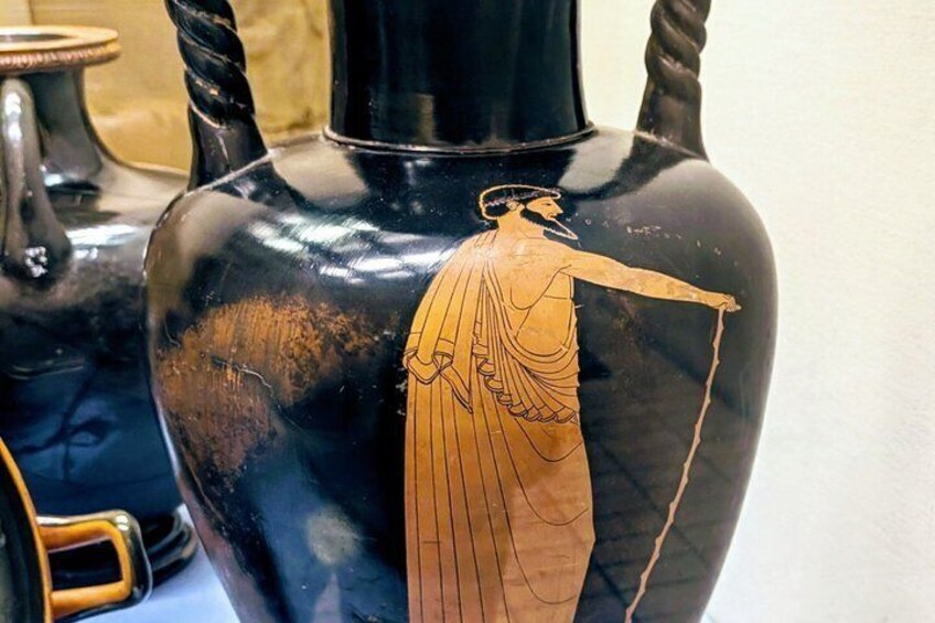 A black vase with a red-figure painting of a female figure. 3