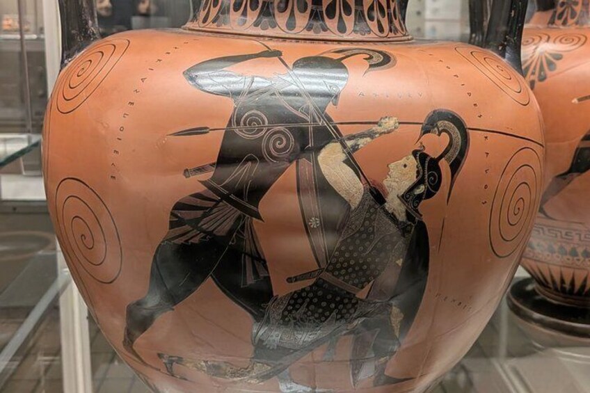 A ceramic vase with black and red painted figures, possibly depicting a battle scene. 5