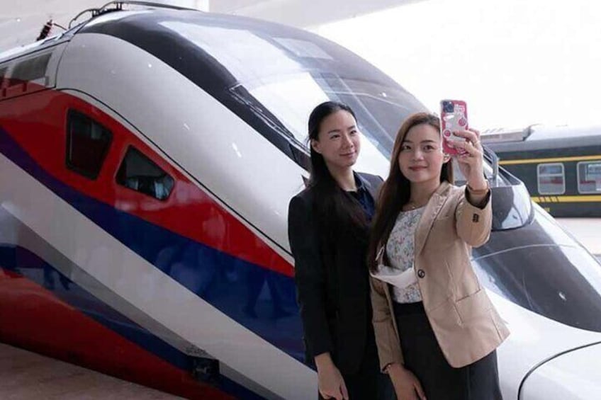 Two people taking a selfie in front of a high-speed train. 3