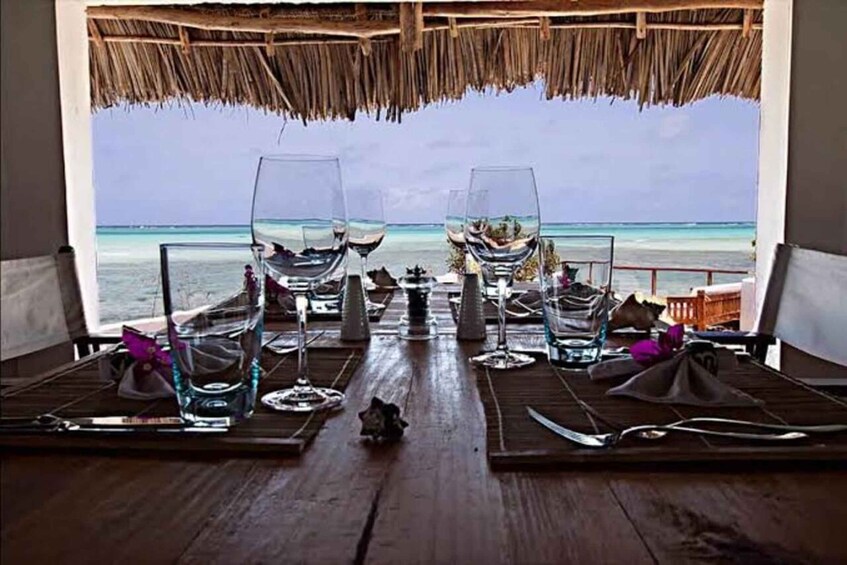 A table set for two with glasses of water and wine, overlooking a beach. 4