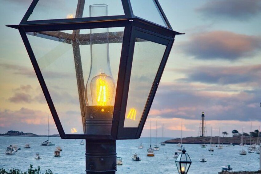 A lantern with a lit bulb, a body of water with boats, and a distant shoreline. 5