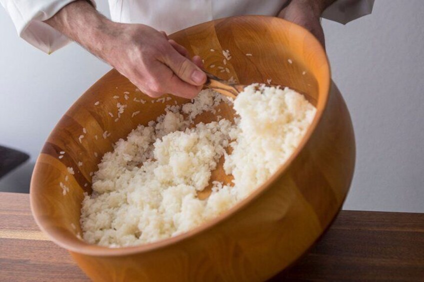 A person mixing rice in a wooden bowl. 2