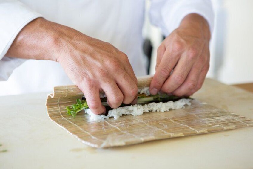 Hands rolling sushi on a bamboo mat. 1