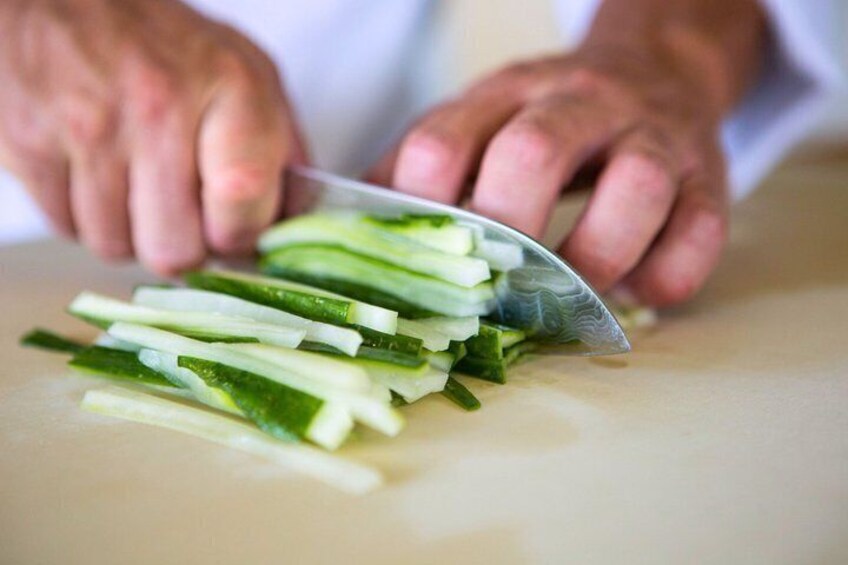 Hands slicing a cucumber on a cutting board. 4