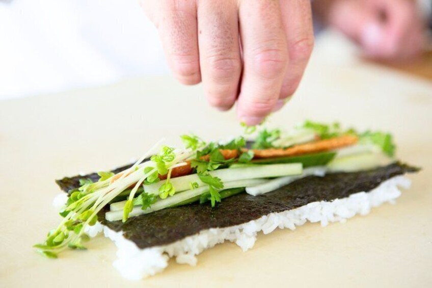 A hand placing a sushi roll on a plate. 5