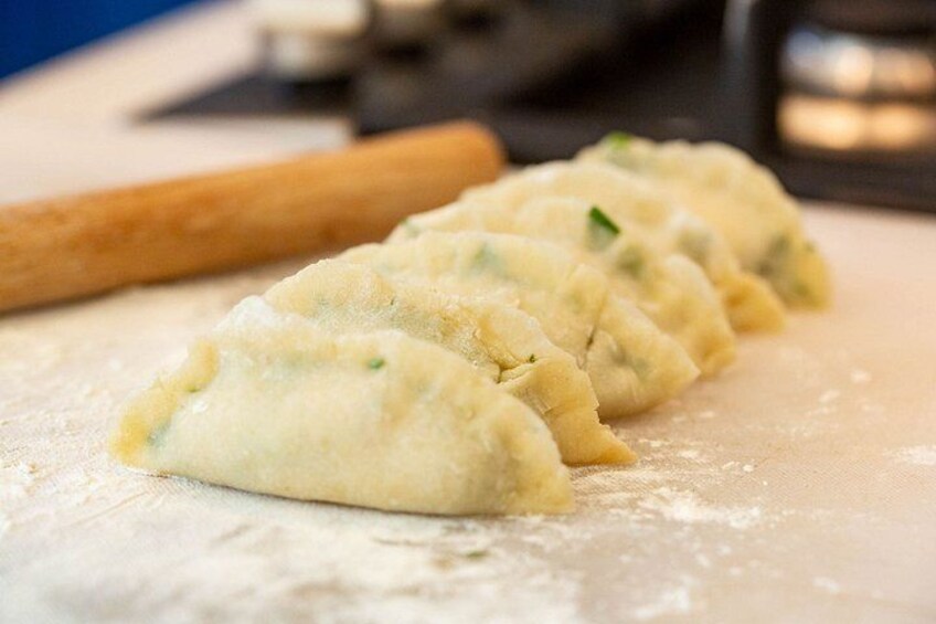A row of dumplings on a floured surface with a rolling pin nearby. 3