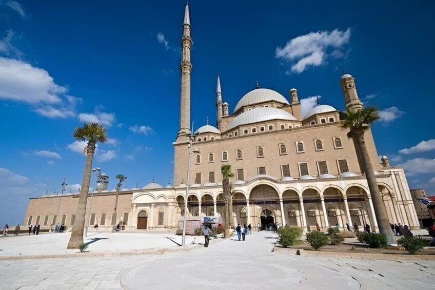 A large mosque with a tall minaret, arched windows, and domes. 1