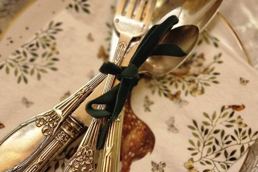 A set of silverware tied with a black ribbon, placed on a floral tablecloth. 2