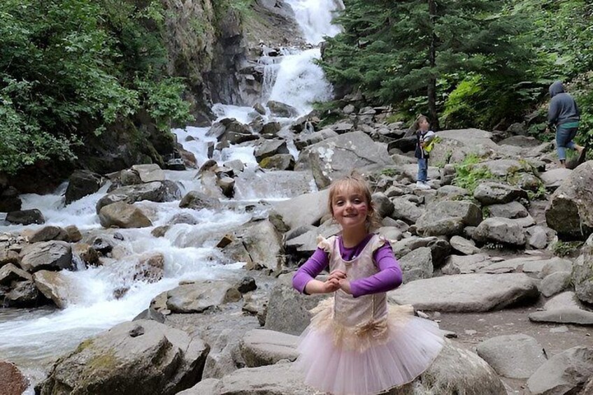 A waterfall, rocky terrain, and a person in a tutu. 2