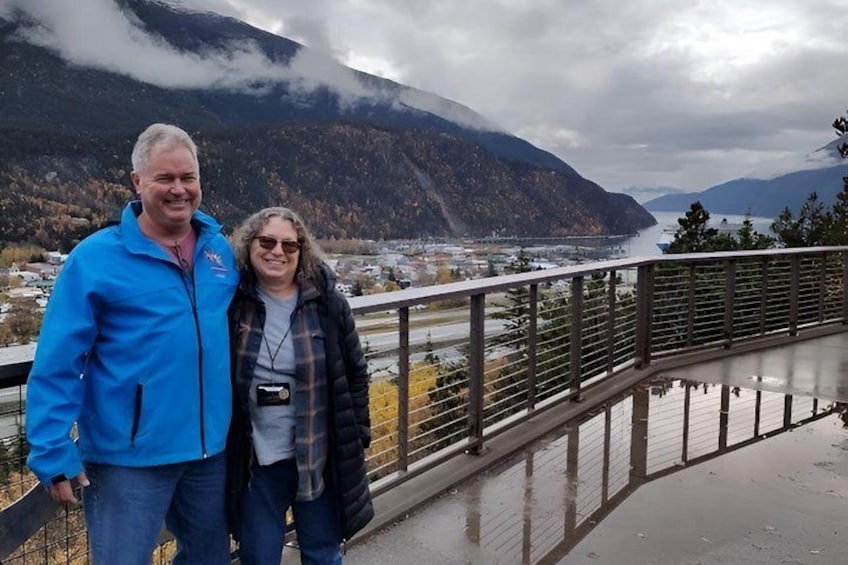 A couple standing on a balcony with a mountainous landscape in the background. 2