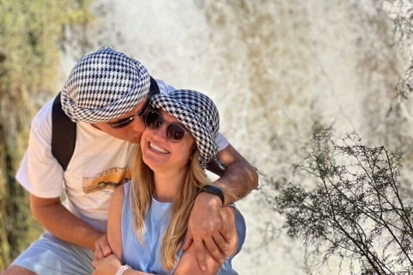A couple embracing in a natural setting with a rocky background. 1