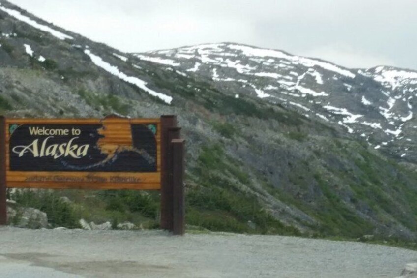 A welcome sign to Alaska with a mountainous backdrop. 4