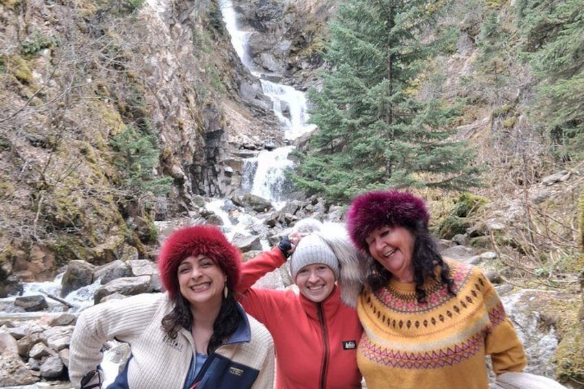 A group of people standing in a mountainous area with a waterfall in the background. 5