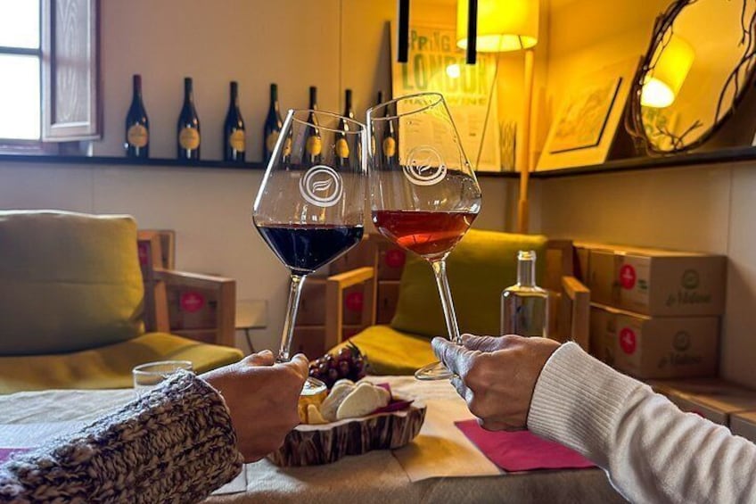 Two people toasting with wine glasses, a bottle shelf, and a cozy seating area. 1