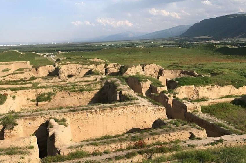 Ancient ruins with stepped structures and a distant mountain range. 2