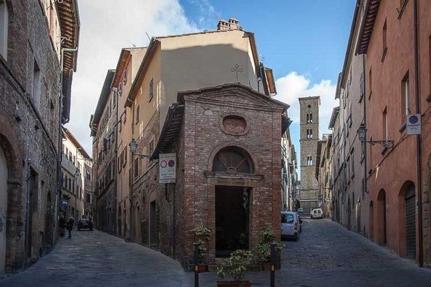 A narrow cobblestone street flanked by historic buildings with a church at the end. 5