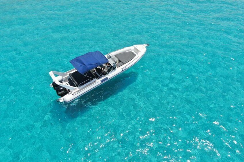 A small motorboat with a blue canopy on clear turquoise water. 2