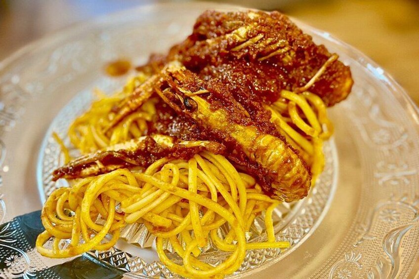A plate of spaghetti with a piece of meat on top. 4