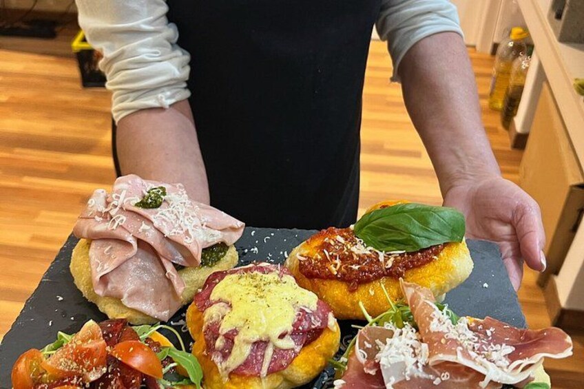 A person holding a tray with various food items including bread, cheese, and meat. 5