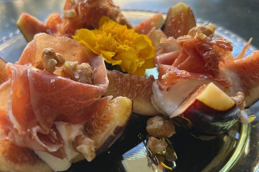 A plate with sliced figs, prosciutto, and nuts. 2