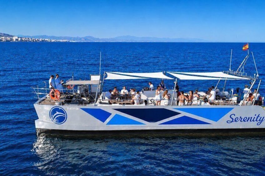 A boat named Serenity with passengers on board, sailing on a blue sea with a clear sky. 1