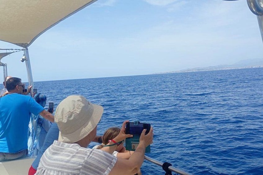 A boat with people taking photos of the ocean. 2