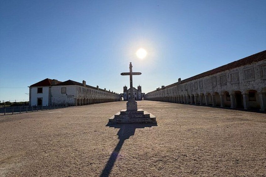 A courtyard with a central monument, surrounded by white buildings with red-tiled roofs. 5