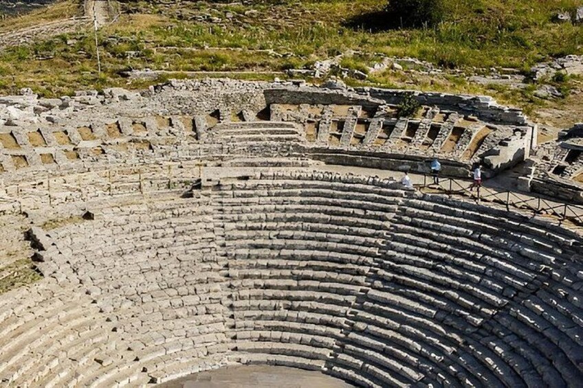 An ancient amphitheater with stone seating and a central stage. 2