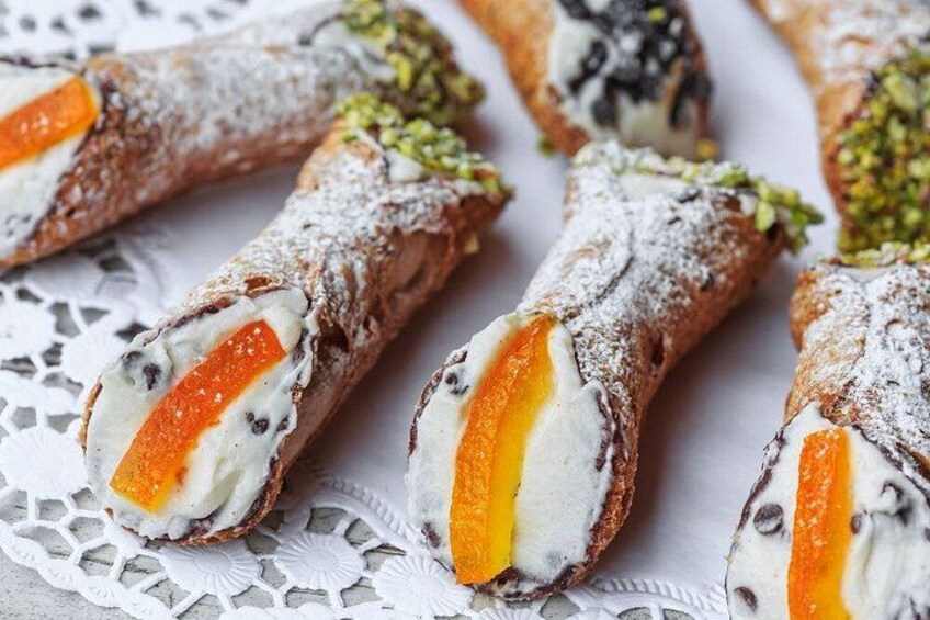 Cannoli with a creamy filling and a slice of orange peel on top, dusted with powdered sugar. 5