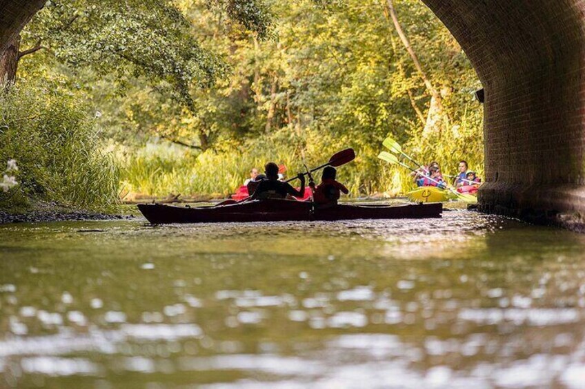 A river scene with kayakers under a bridge. 2