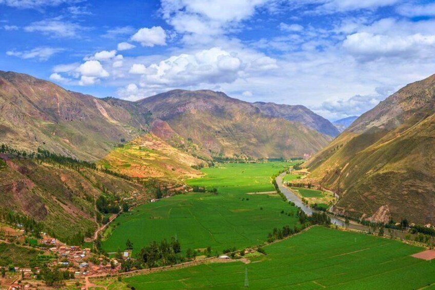 A valley with a river, green fields, and mountains. 3