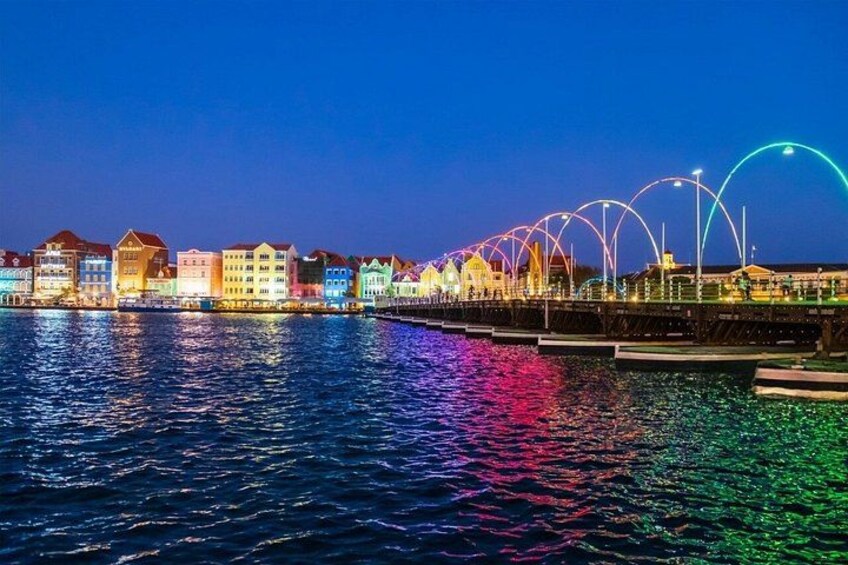 Een waterkant met kleurrijke gebouwen en een felverlichte boog. 3