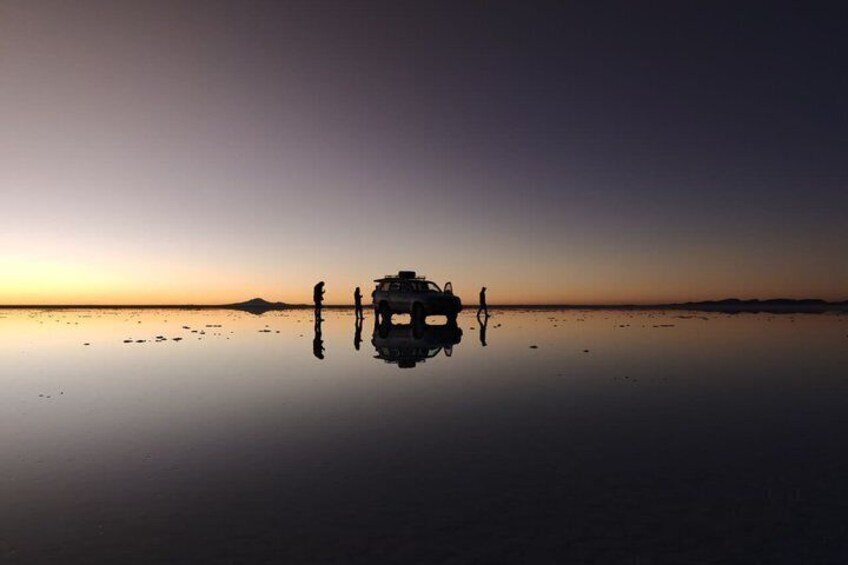 A vehicle on a reflective water surface with a sunset in the background. 4