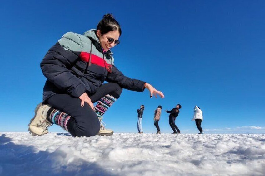 A person crouching on snow with others standing in a line. 5