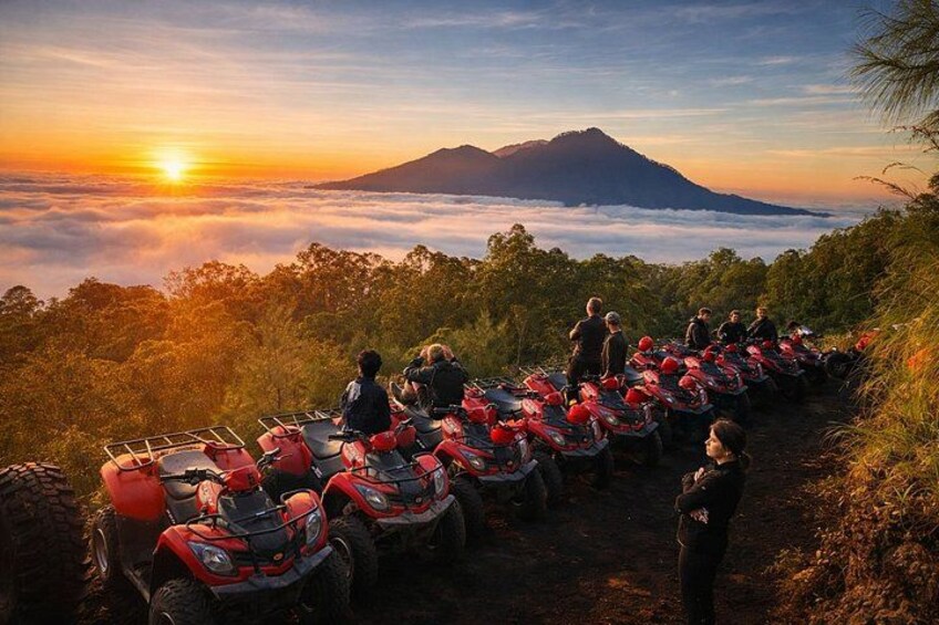 A group of people on a mountain trail with red ATVs parked along the path, overlooking a sunrise with clouds below. 5