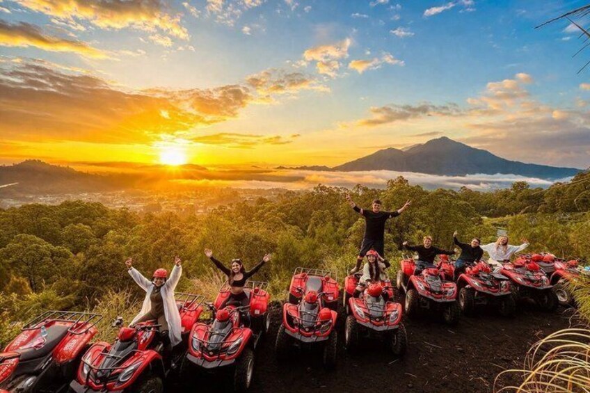 A group of people with quad bikes on a hilltop during sunset, with a mountain and clouds in the background. 5