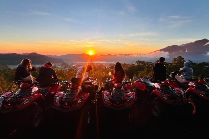A group of people on quad bikes at sunset with a mountainous landscape in the background. 2