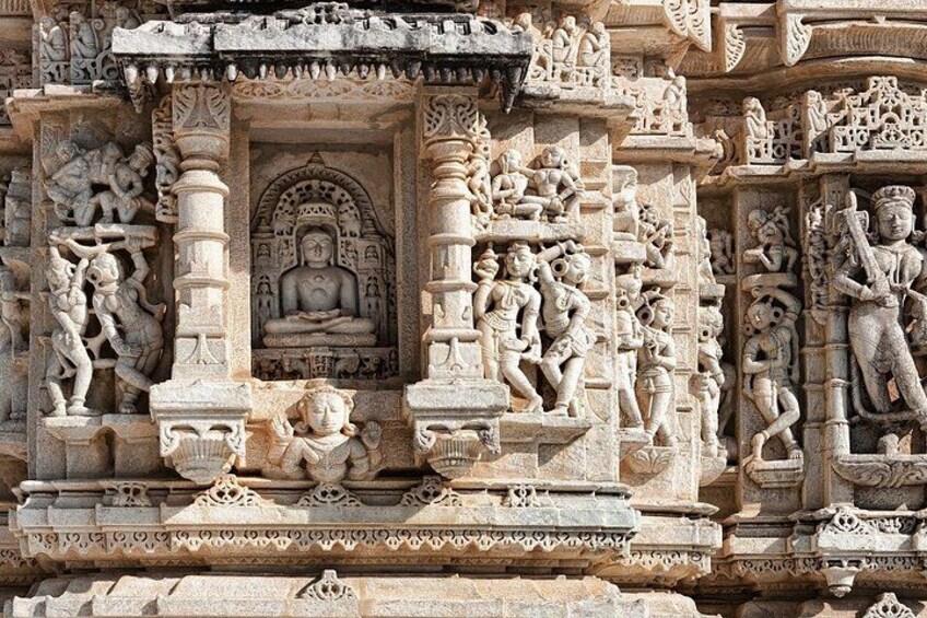 A detailed stone carving with a central figure in a meditative pose, surrounded by smaller figures and intricate patterns. 4