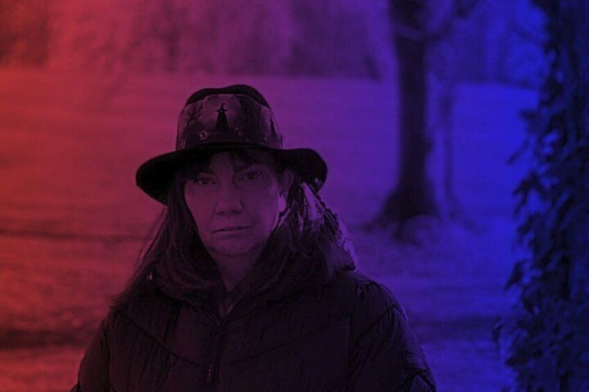 A person in a dark jacket and hat standing in a snowy landscape with trees in the background. 5