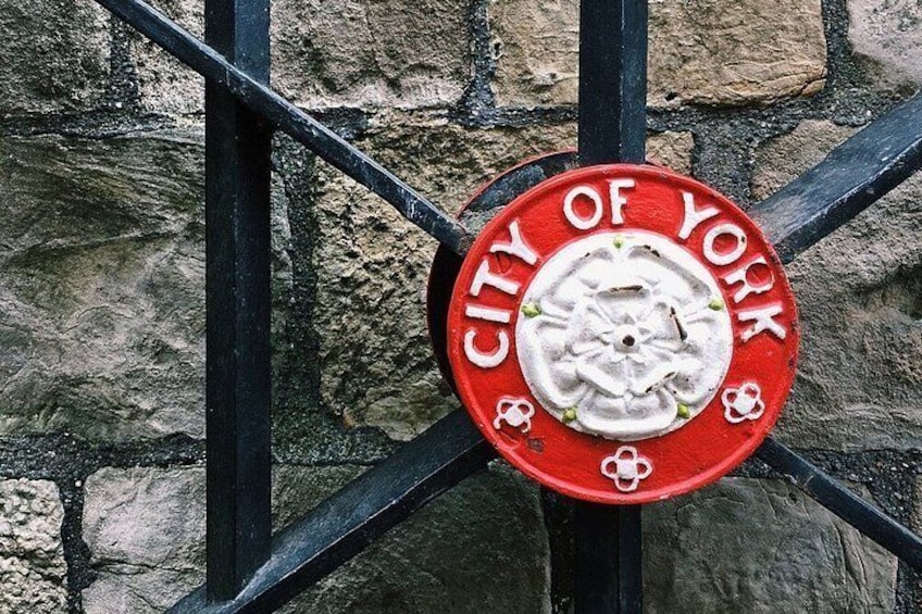 A red plaque with 'CITY OF YORK' text and a white emblem on a metal gate. 2