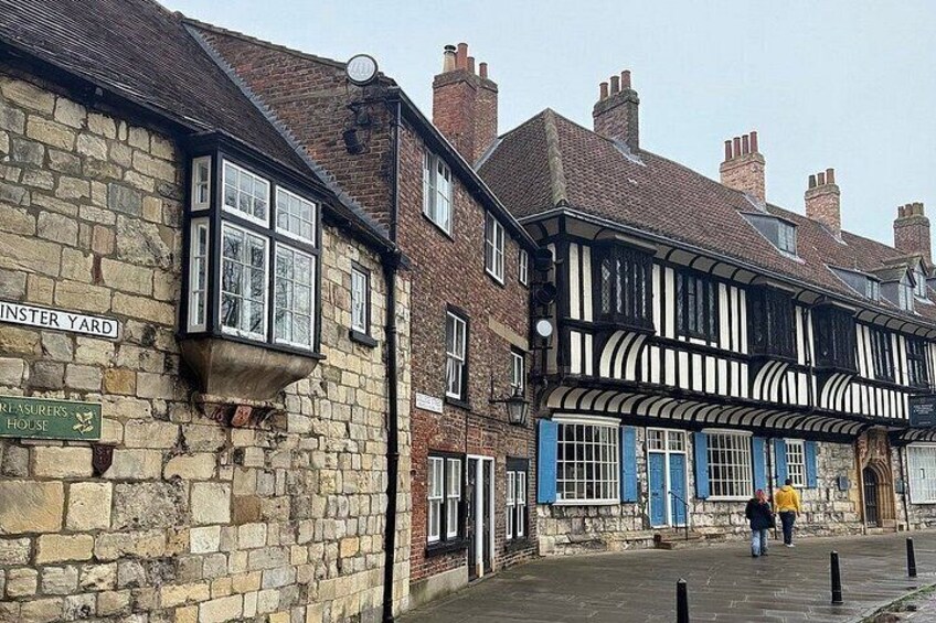 A historic street with Tudor-style buildings, a sign for 'Minster Yard,' and a 'Raisers' House.' 3