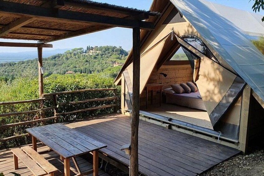 Una terraza de madera con una estructura tipo tienda de campaña, un espacio de descanso con cojines y vistas a un paisaje montañoso. 1