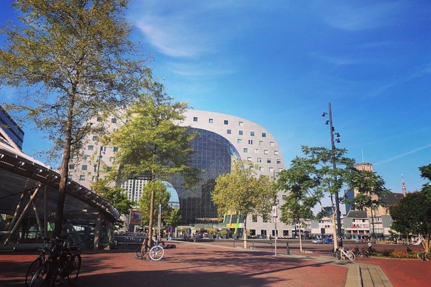 A modern building with a curved glass facade, surrounded by trees and a red brick plaza. 2