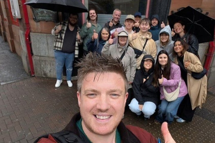 A group of people posing for a photo outside a building with a brick facade. 1
