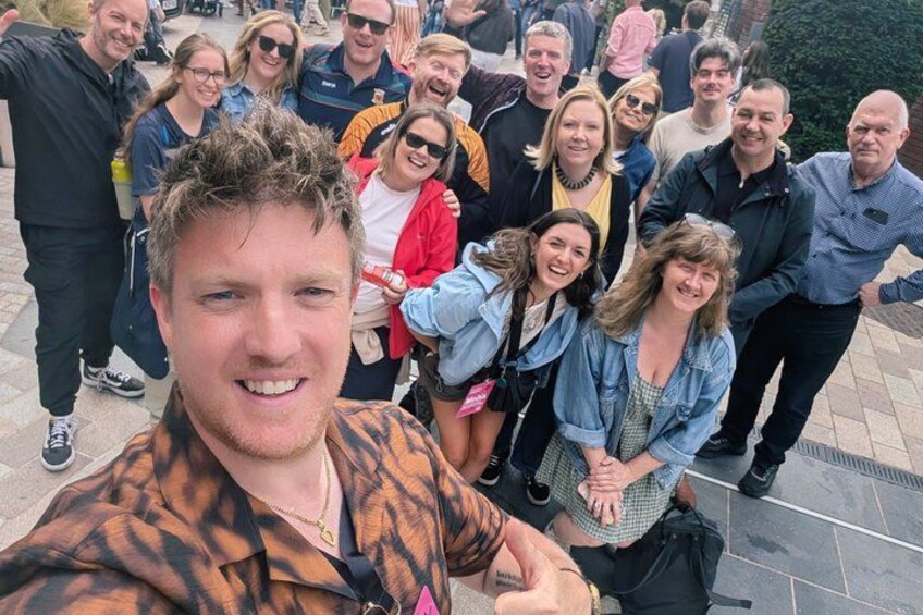 A group of people standing on a paved area with a stone wall in the background. 5