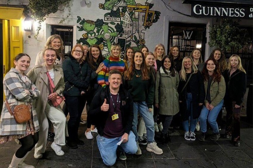 Un gruppo di persone che posa di fronte a un murale, con un cartello Guinness sullo sfondo. 5